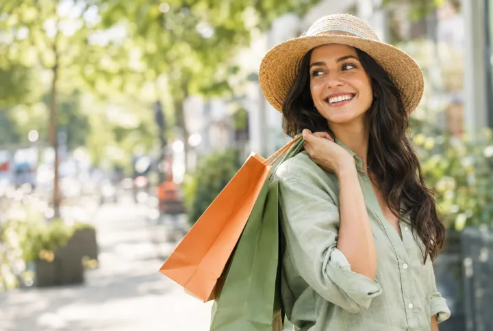 Smiling shopper carrying shopping bags on a sunny street